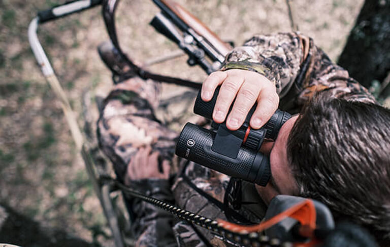 Hunter in tree stand looking through Nitro Binoculars